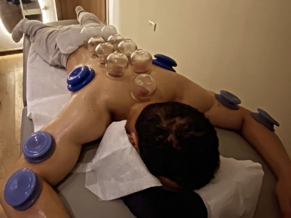 Client face down on the table with glass cups along the spine and silicone cups on the arms